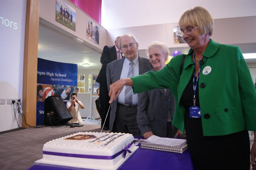 Jean Lane, Harrogate High School's vice chair of governors, cutting the 50th anniversary cake while John and Ada Shorter look on.