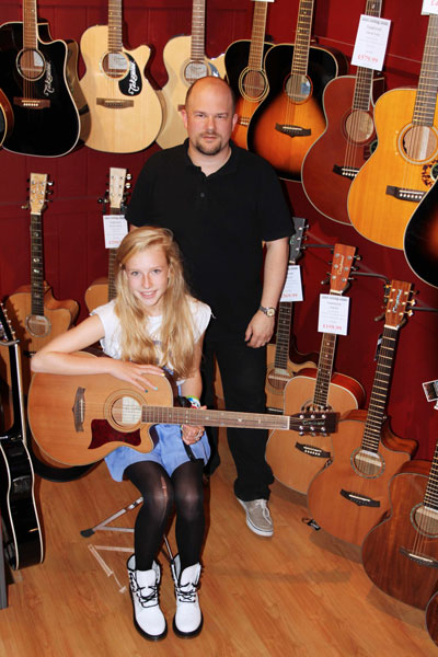 13-year old singer/songwriter Billie Tweddle picking up her guitar from  Phil Dean owner of Rock Steady Music in Harrogate