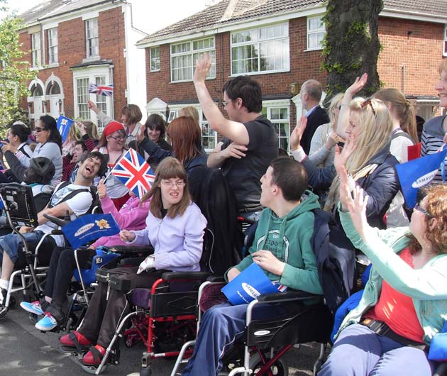 Students from Henshaws College line the streets with flags and banners to welcome the Olympic torch