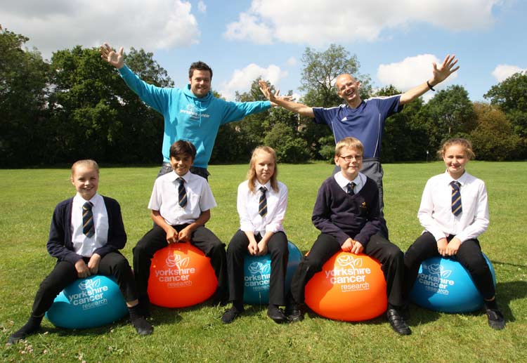 Andy Pierce, Events Manager at Yorkshire Cancer Research, and Mr Tim Pocock, Charities Co-ordinator at St Aidan’s CE High School, with students on space hoppers