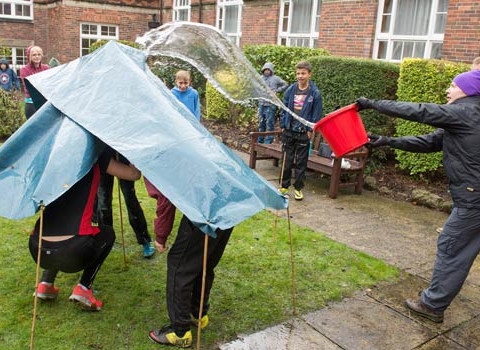 Year 9 students finding out whether their hand-built shelters are waterpro