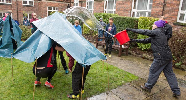 Year 9 students finding out whether their hand-built shelters are waterpro