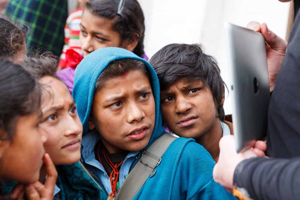 Students from Shree Gaun Pharka LSS look on in wonder as Callum Morrison shows them a video of themselves on an iPAD