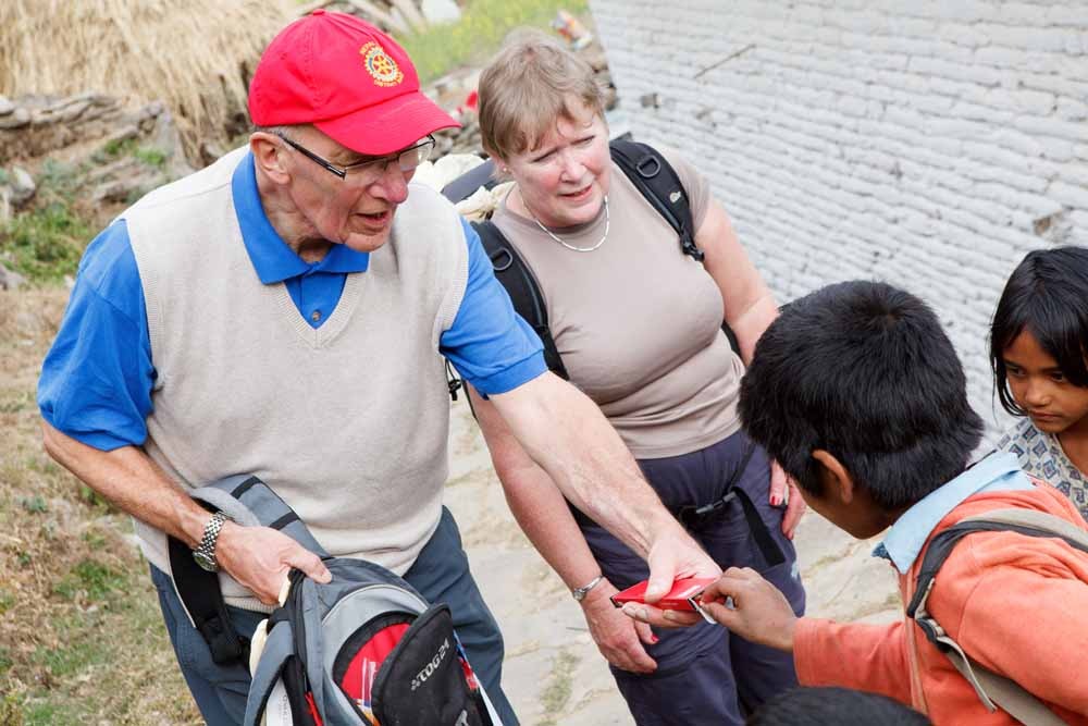 Rotarians Barry Pollard and Gill Poole hand out pencils to local children