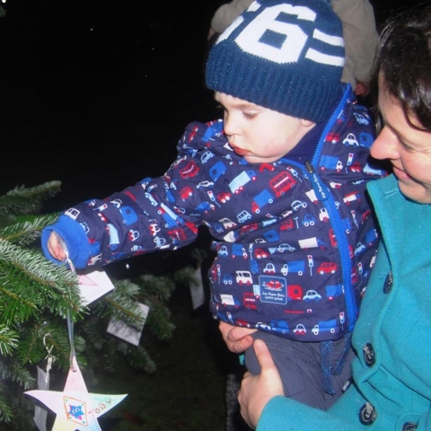 a mother and son hang a star on the Saint Michael’s tree at one of two special remembrance services