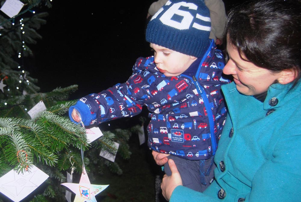 a mother and son hang a star on the Saint Michael’s tree at one of two special remembrance services