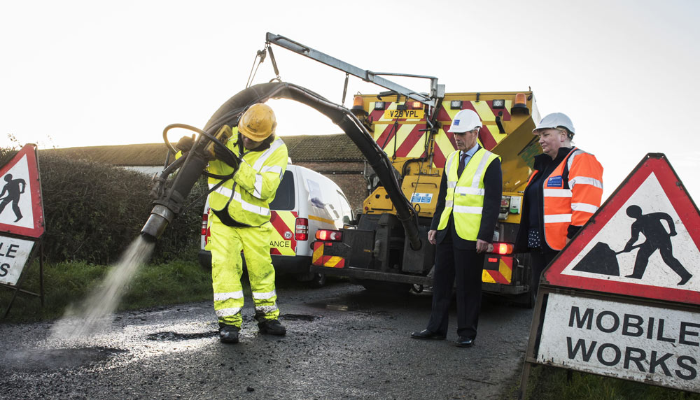 County Councillor Don Mackenzie and Highways Customer Communication Officer Deborah Flowers see a jet patcher in action