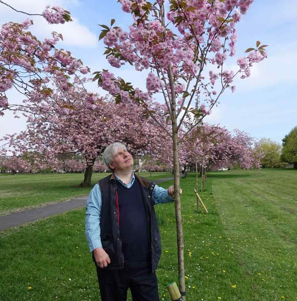 Harrogate resident Guy Tweedy and one of the 12 trees planted in memory of his former Headmaster, Geoffrey Raspin