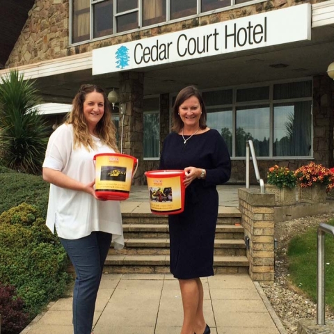 Tracey Ractliffe, Cedar Court Hotels Group Director of Sales & Marketing receives collection buckets from Yorkshire Air Ambulance Director of Marketing and Communications Abby McClymont