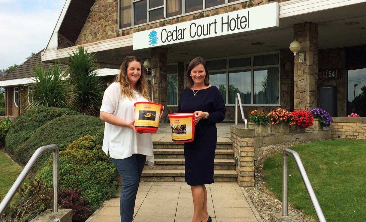 Tracey Ractliffe, Cedar Court Hotels Group Director of Sales & Marketing receives collection buckets from Yorkshire Air Ambulance Director of Marketing and Communications Abby McClymont