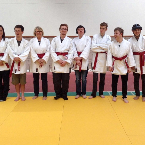 Henshaws Specialist College students celebrate achieving their red belts with staff and coaches