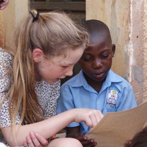 Highfield Prep School pupil reading with a pupil from Bombo village school in Uganda