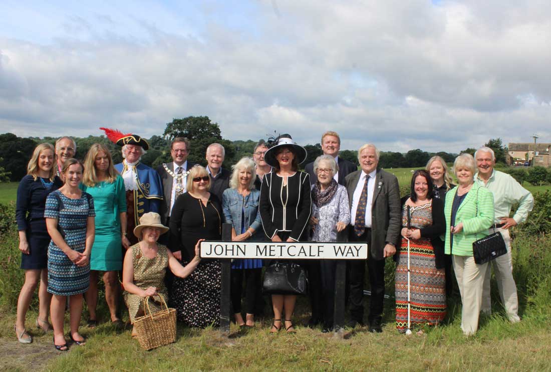 John Metcalf Way sign unveiling 2: Councillor Anne Jones, Mayor of the Borough of Harrogate; Councillor David Goode, Mayor of Knaresborough; Roger Hewitt, the Town Crier of Knaresborough;  local historian Brian Forshaw; Bernard Higgins and other representatives from the Blind Jack of Knaresborough Tri-centennial Anniversary Committee, the FEVA Knaresborough committee and Welcome to Yorkshire celebrate the unveiling of  the road sign in honour of John Metcalf