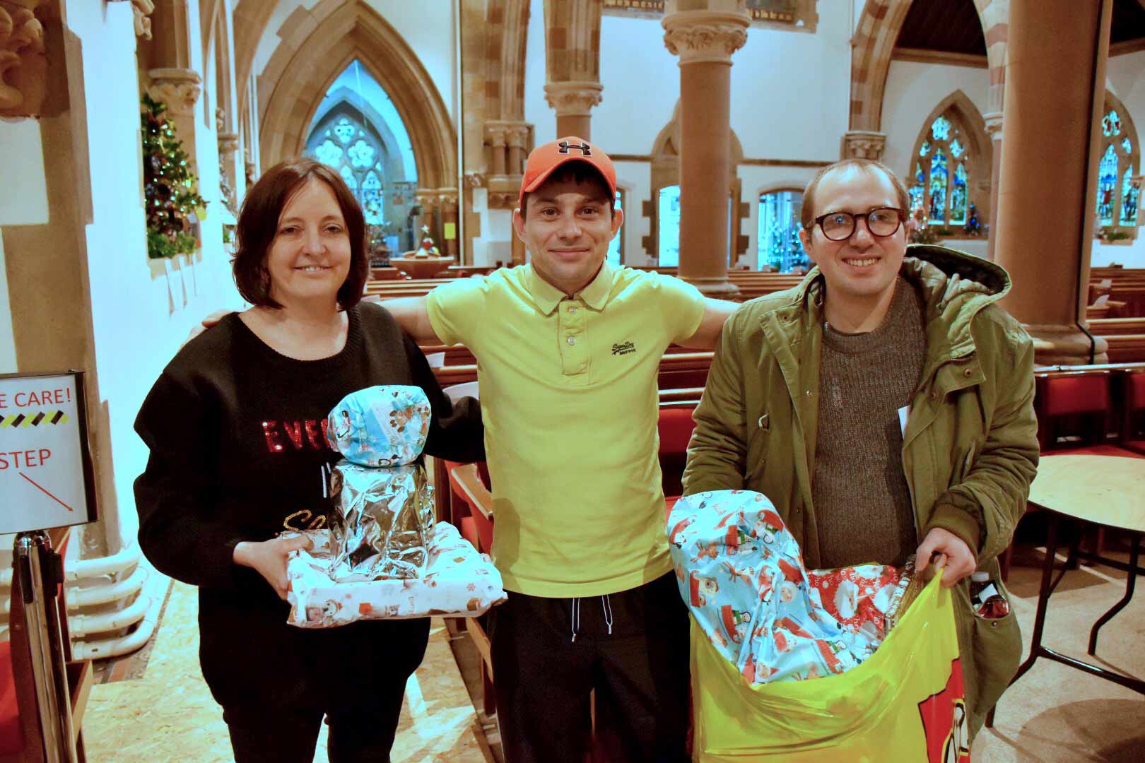 A parent accepts gifts from Sue Johnston, teaching assistant, and adult learner Dane Hogg (right)