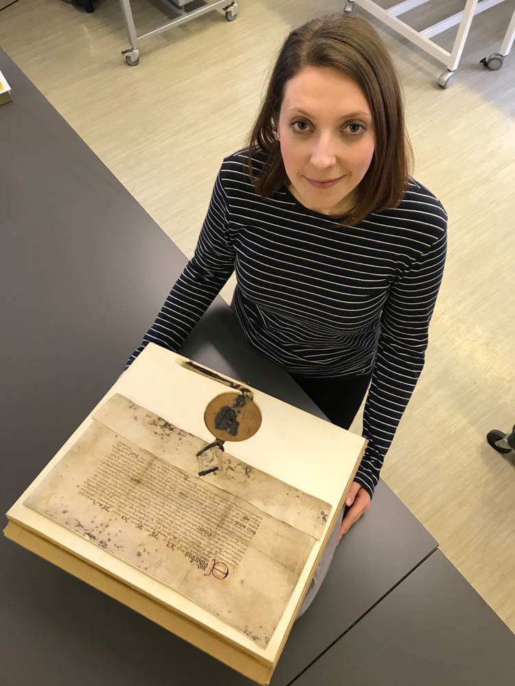 One of the many historic documents preserved by the County Record Office. Emily Ward, Record Assistant, with a grant bearing the great seal of Edward IV, 1478