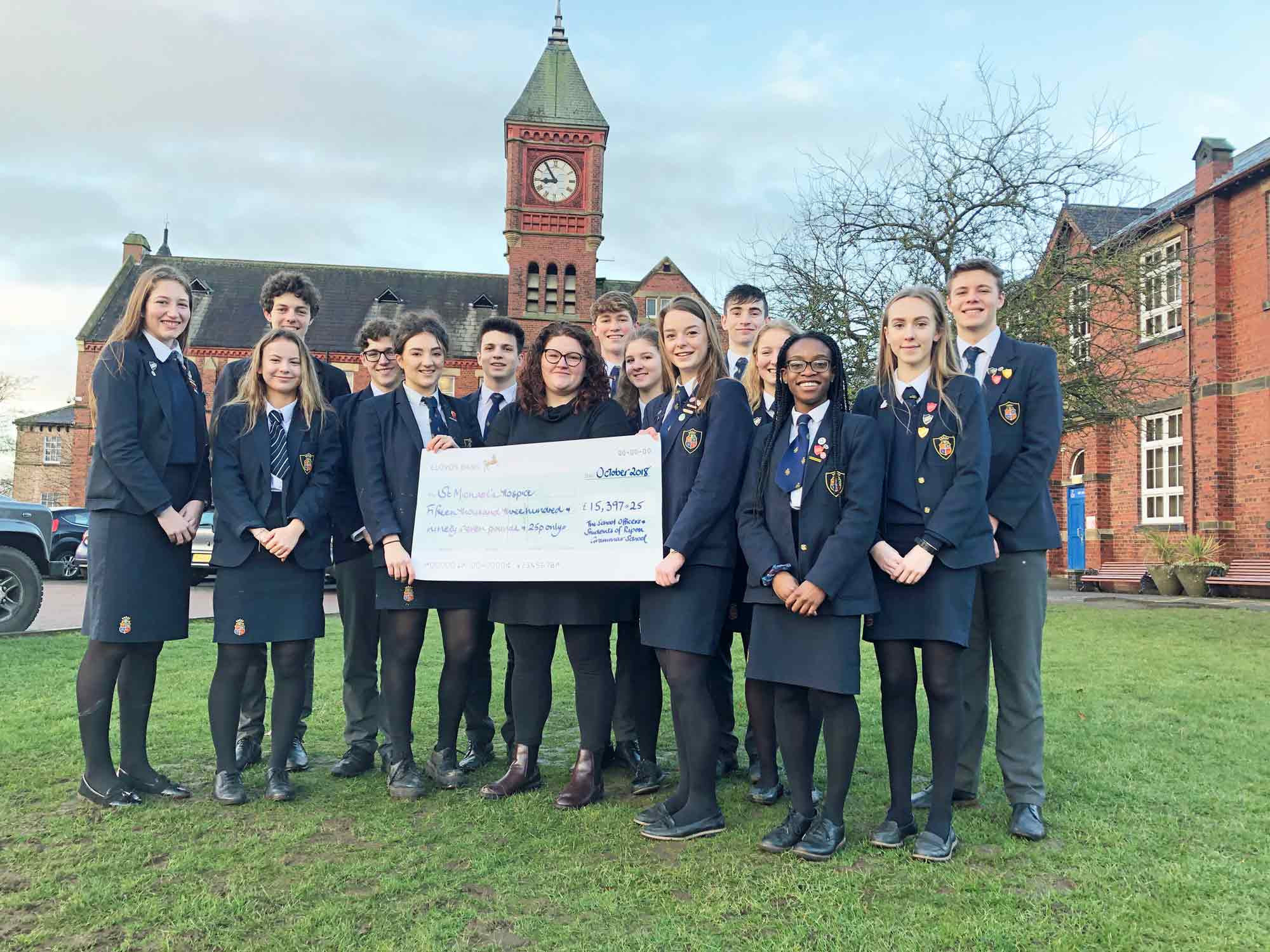 Record-breaking: Grace Withyman, left, and Louise Taylor, right, surrounded by their fellow students, present the £15,397 cheque to St Michael's Hospice fundraiser Beth Crewe