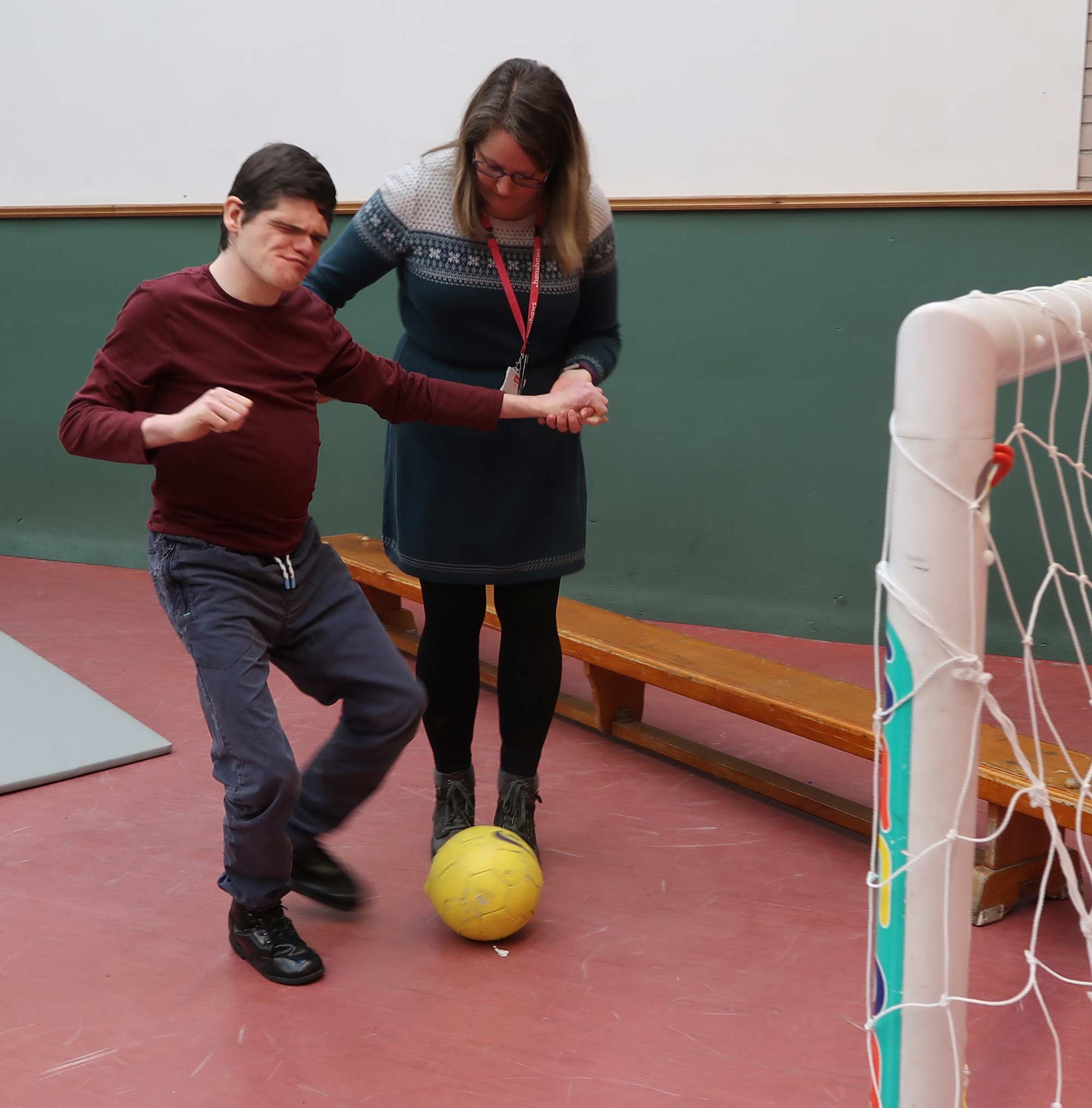 Student Andrew Fletcher who has been working on rolling a ball goes for goal with the help of Johanne* Dodsworth