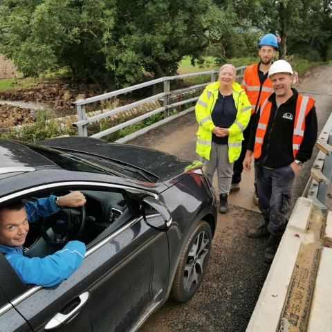 Pictured, Andrew Atkin, landlord of The Bridge Inn at Grinton, prepares to be the first person to drive along the reopened section of the B6270 this afternoon, watched by (from left) Deborah Flowers, County Council highways communication officer, Phil Richardson, senior engineer from the County Council’s bridges team, and Andy Lacy, director of contractor Hinko