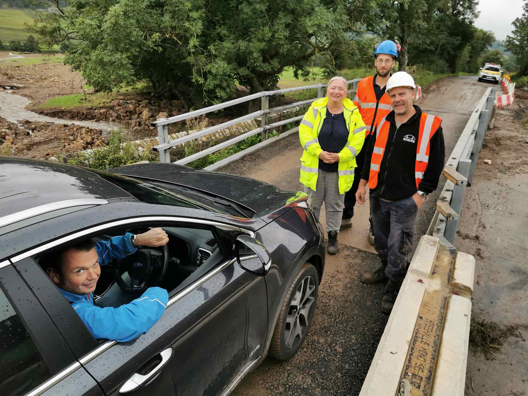 Pictured, Andrew Atkin, landlord of The Bridge Inn at Grinton, prepares to be the first person to drive along the reopened section of the B6270 this afternoon, watched by (from left) Deborah Flowers, County Council highways communication officer, Phil Richardson, senior engineer from the County Council’s bridges team, and Andy Lacy, director of contractor Hinko
