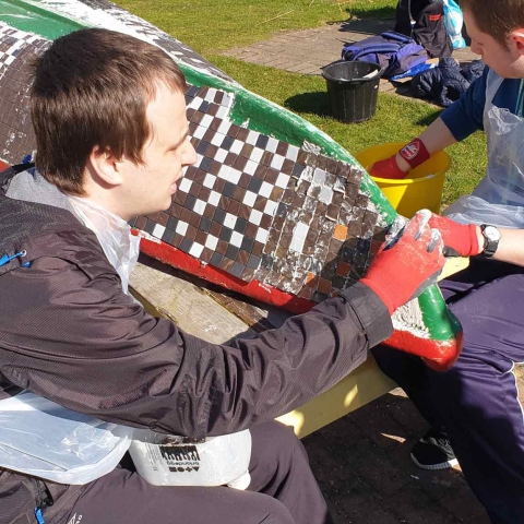 Matthew Turner and George Crouch work on the mosaic-covered boat