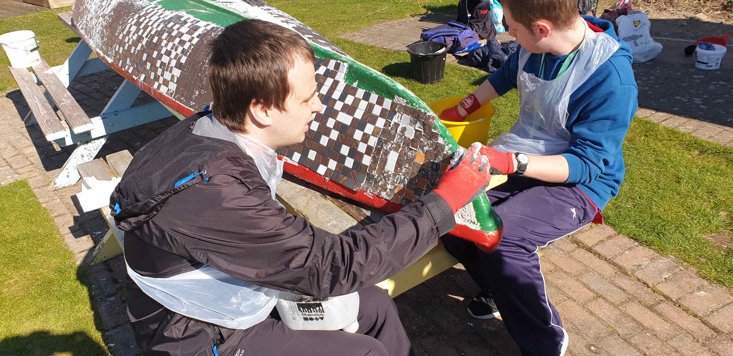 Matthew Turner and George Crouch work on the mosaic-covered boat