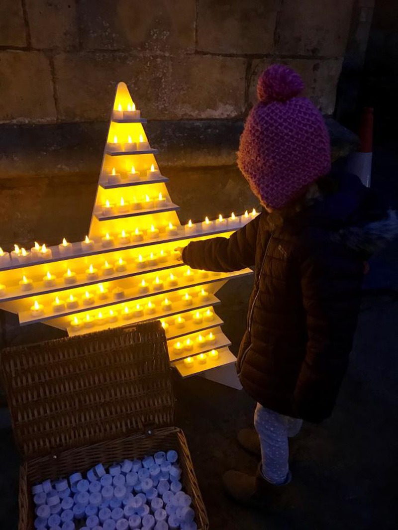 Saint Michael’s young supporter, lighting a candle in memory of her father, as part of last year’s Twilight Walk