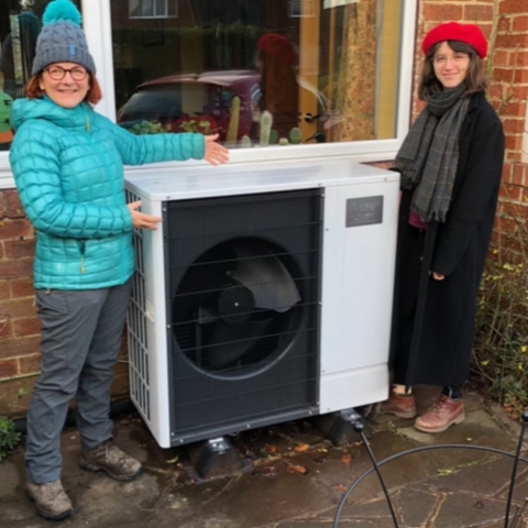 Kirsty Hallett (Chair of Harrogate District Climate Change Coalition Communications and Engagement Sub-group) demonstrating an air source heat pump (ASHP) which provides ample central heating and hot water for a local home. As burning fossil fuels in gas boilers is being legally phased out by the government, ASHPs will be used to heat most homes and many commercial spaces and hot water supplies using only renewable electricity.
