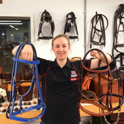 Lance Bombadier Farren holding handmade bridles in the saddlery