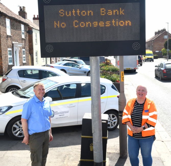 Councillor Gareth Dadd and North Yorkshire County Council Highways Communications Officer Deborah Flowers under the new signage on Long Street in Thirsk