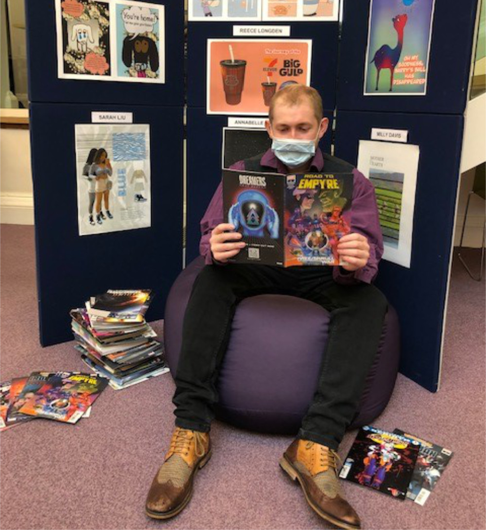 Library assistant Tom Bamford, sitting in front of the exhibition at Harrogate library, samples one of the comics in the giveaway