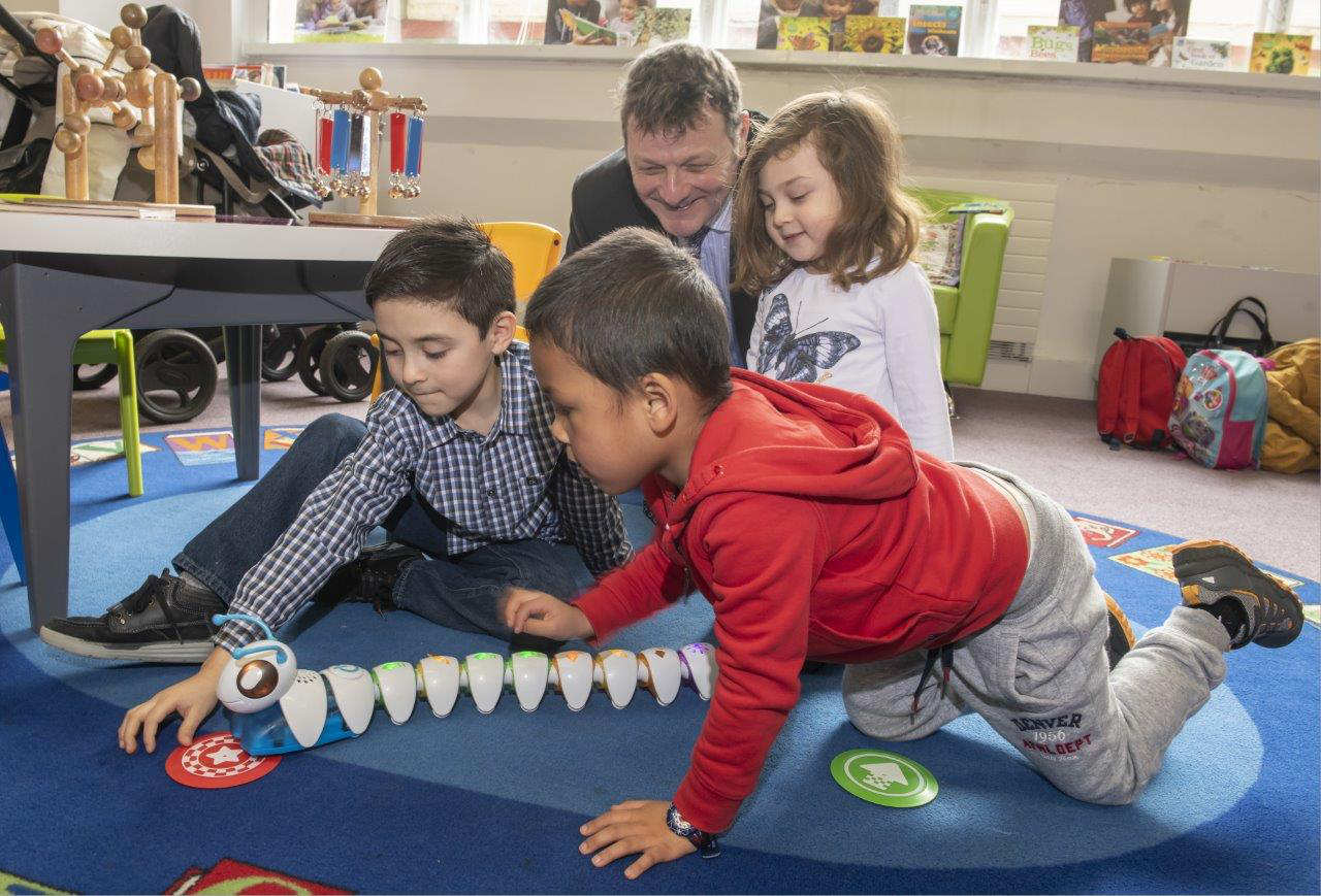 Councillor Greg White with children using a code-a-pillar at a digital family fun day at Harrogate library