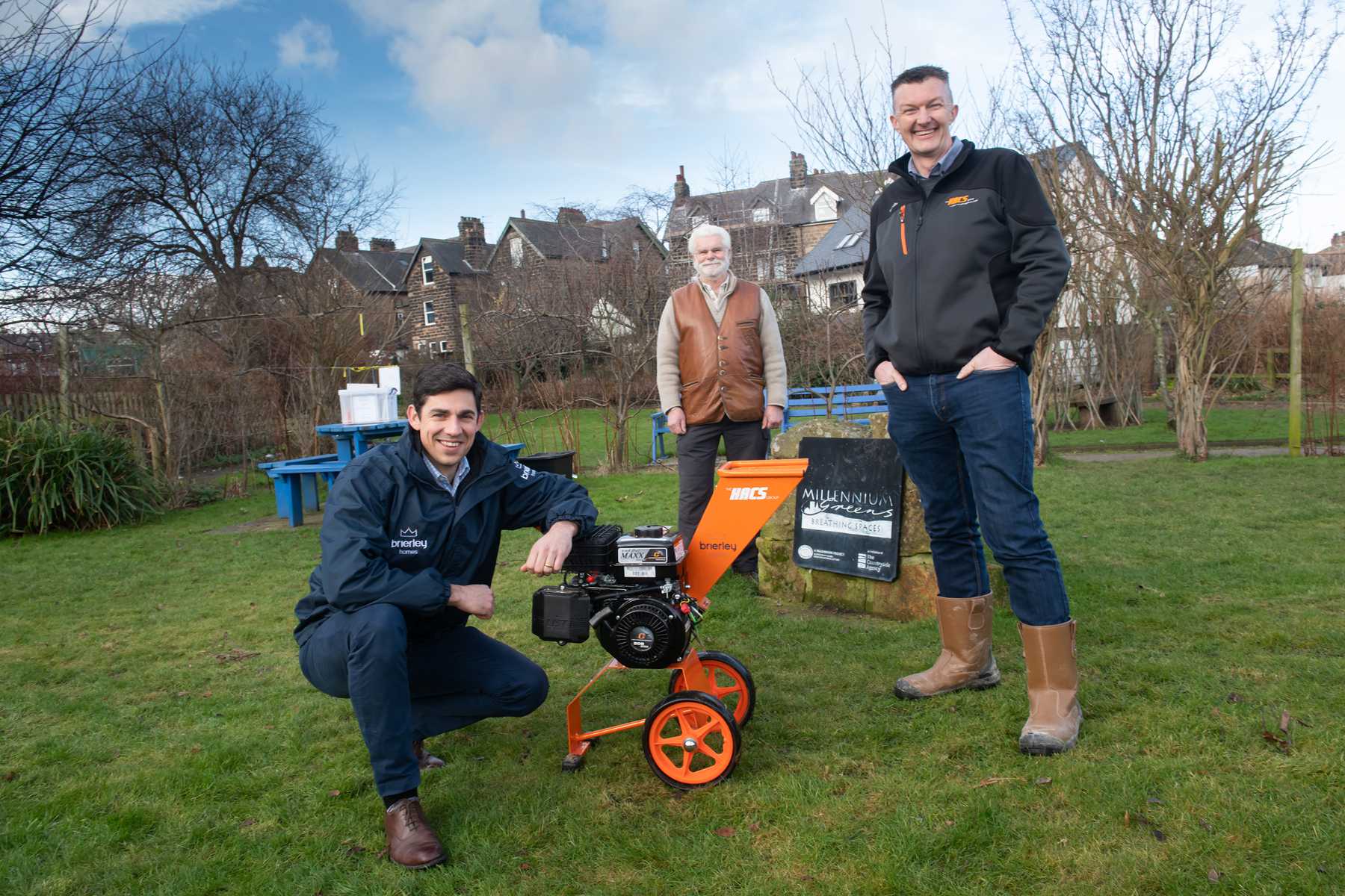 Mike Craddock from Brierley Homes, John Hart, Chair of the Trustees of the Woodfield Millennium Green, and Eddie Ashworth from The HACS group, with the wood chipper