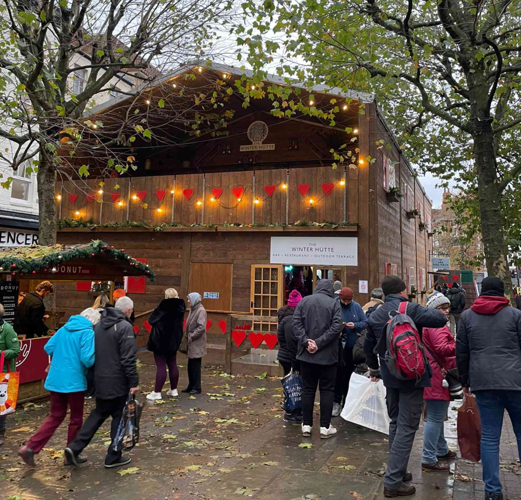 SWISS CHALET POP-UP BAR & RESTAURANT OPENS AT YORK CHRISTMAS MARKET TO FANFARE FROM ALPINE HORN AND CAPACITY VISITORS [21 NOVEMBER 2022, YORK]: York’s newest Christmas attraction opened on Friday to a fanfare with a difference – from a traditional alpine horn. The Winter Hütte Swiss-style bar and restaurant brings a true taste of the Alps to York’s Christmas Market and during its opening weekend entertained thousands of residents and tourists who came to enjoy the new ski lodge ambience, with capacity visitors in the bar and over 800 people served in the upstairs restaurant. The two-storey Winter Hütte is a traditional wooden chalet built around a marquee structure, complete with mountain views, red shutters, window boxes, and even rustic cow bells. The pop-up venue comprises a fully-licensed bar area downstairs serving seasonal favourites such as gluhwein and hot chocolate, as well as a special Alpine Star beer from Brew York and a range of cocktails and wines. A gourmet sausage stall The Dog Haus caters for bar patrons as well as passers-by outside. With its Alpine folk motif curtains, vintage ski posters and sheepskin-covered wooden stools, The Winter Hütte’s apres-ski bar evokes a cosy mountain refuge, with a large stone fireplace and woodburning stove, and window views of snowy village scenes. With live music performances and the scent of gluhwein and bratwurst, The Winter Hütte offers an experience for all the senses this Christmas. Upstairs The Star Inn at The Winter Hütte brings a relaxed bistro-style restaurant and Swiss-with-a-twist food from one of Yorkshire’s Best-known chefs, the Michelin-starred Andrew Pern, while the outdoor terrace makes a picturesque setting for a festive drink overlooking the Christmas Market. With a broad menu including traditional favourites such as fondue and tartiflette as well as off-piste specials such as pheasant with smoked garlic and a ‘Mont Blanc’ dessert, the ambience is completed by antler chandeliers and stunning black and white vintage photographs from the Swiss village of Zermatt, creating an authentic and cosy dining experience, with table-sharing in true apres-ski style. Booking is recommended for the restaurant as well as the outdoor drinks terrace at www.winterhutte.co.uk. A deposit of £15 per person is required for the booking and will be fully redeemable against the final bill. For full terms and conditions, please visit the website. The Winter Hütte is open every day from 17th November 2022 until 1st January 2023, from 9.30am until 11pm (closed on Christmas Day). For any general enquiries, please visit the website or email the team at CanIAlpYou@winterhutte.co.uk. The Winter Hütte is part of St Nicholas Fair, York’s Christmas Market, in collaboration with Make It York. The Winter Hütte is a joint venture between Coopers Marquees, CMJ Events and The Star Inn the City (York). Combined, the team brings over 60 years of live entertainment and food knowledge to deliver this spectacular new event for York, home to all three companies.