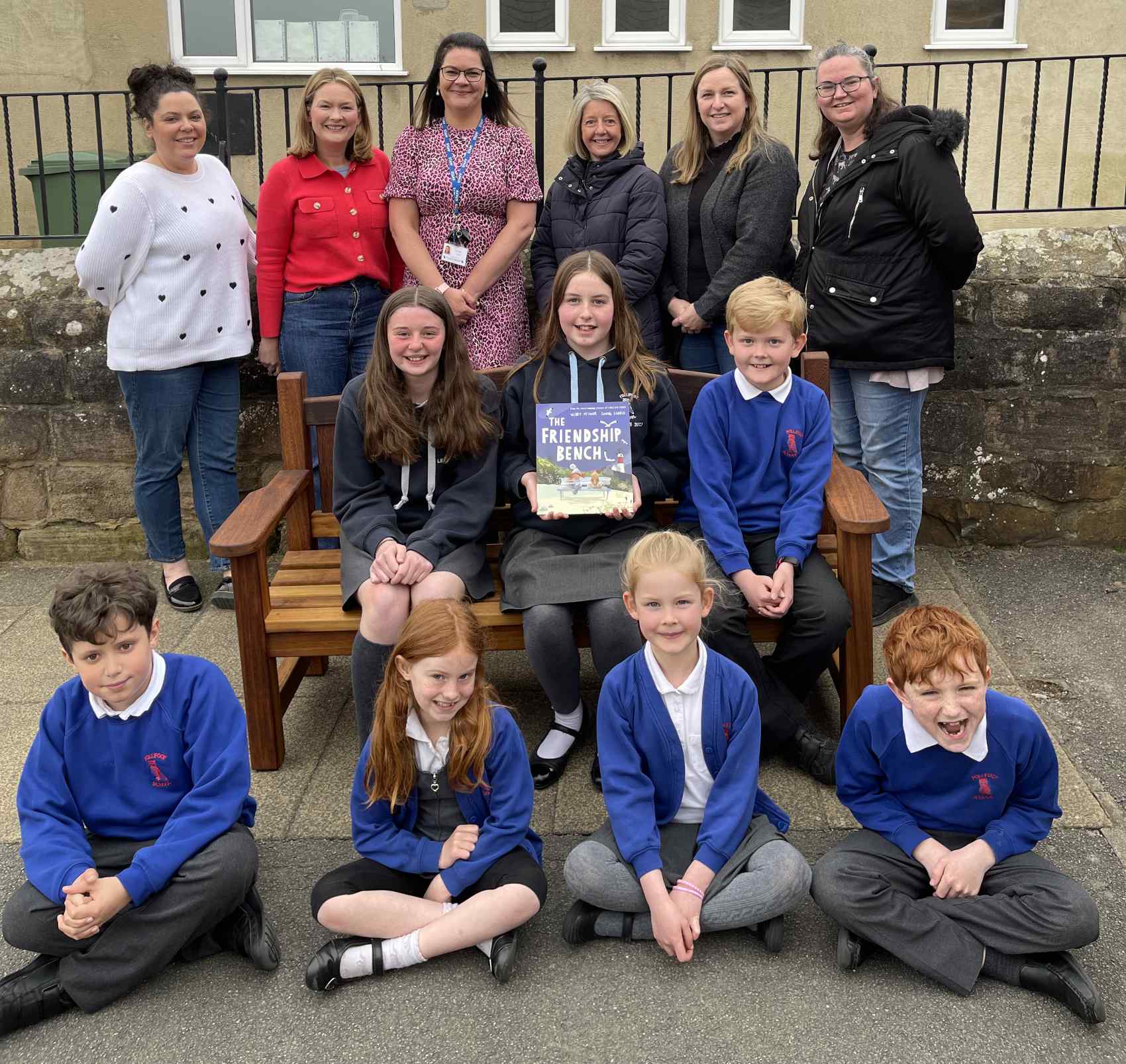 Friends of Follifoot School present Friendship Bench to Follifoot school children Back row L to R: Sophie Griffiths from Harvey George Limited; Laura Hartley, Chair of FOFS; Rebecca Holland, Headteacher at Follifoot Primary School; Claire Hartley, Vicky Hodgson and Sam Riley from FOFS Middle row L to R: Lizzie, Annabelle, William Front row L to R: Elliot, Jessica, Florence, Jasper