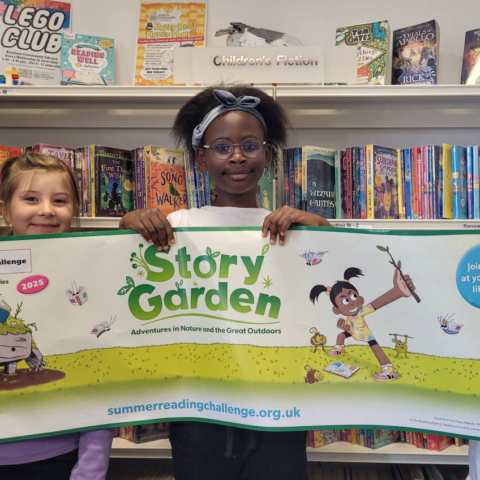 From left, Rita, Sharon and Lotan from Bentham Community Primary School, showing off the Story Garden Summer Reading Challenge banner