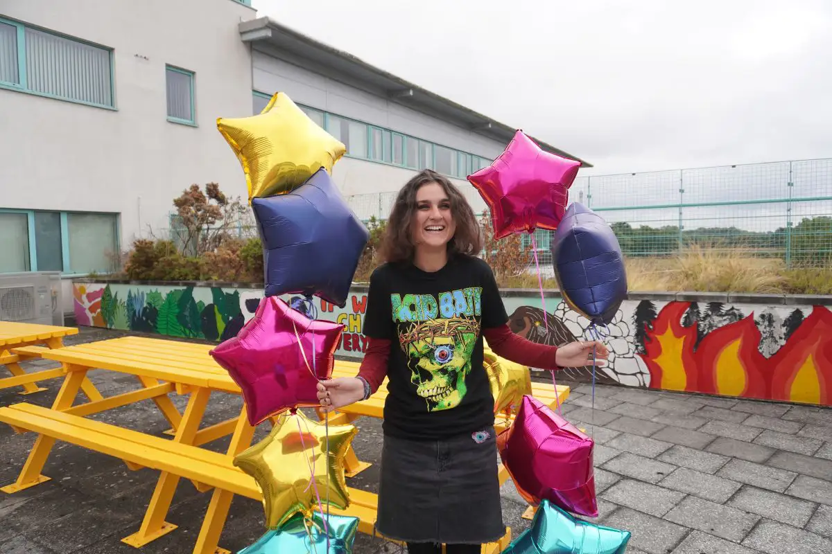Winnie Parry celebrates her GCSE results holding star-shaped balloons in the York College Podium Garden